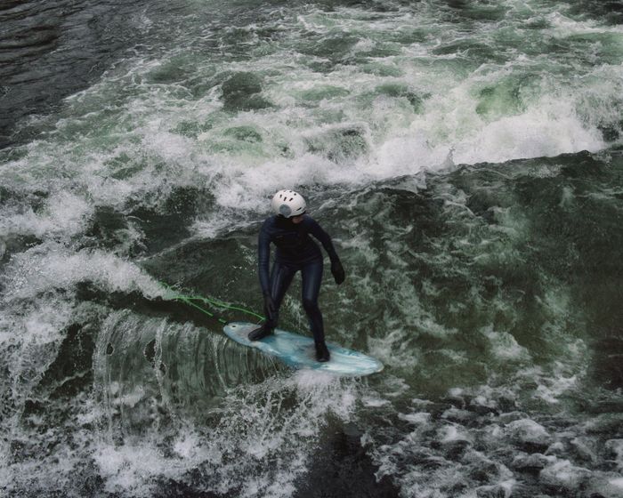 A surfer skillfully navigates the waves on a river in Munich, Germany.