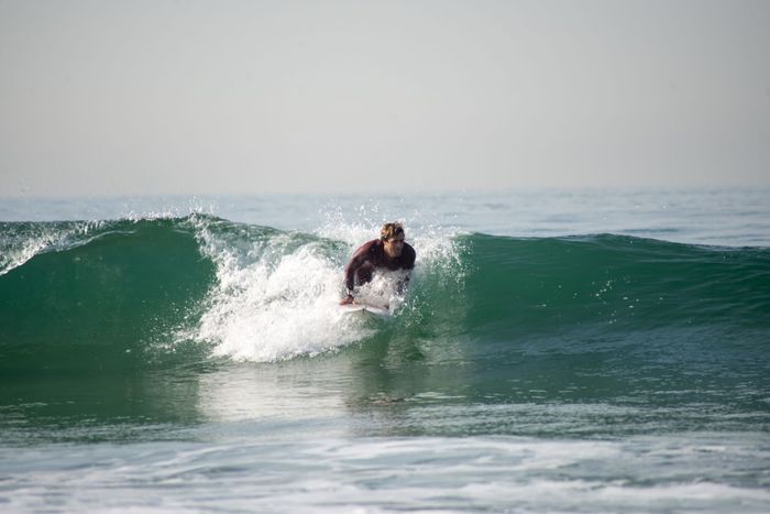 A surfer skillfully rides a wave on a sunny day at a Portuguese beach, showcasing the thrill of surfing.