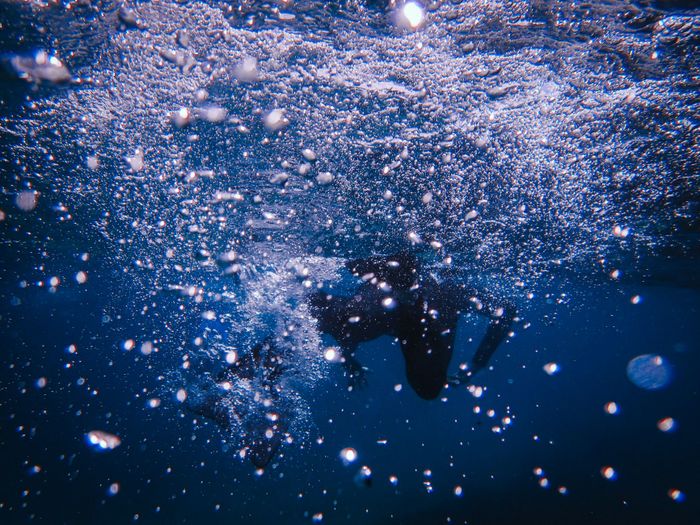 Dramatic underwater shot capturing dynamic bubbles and silhouette of a diver.