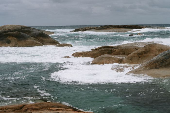 Waves crash over rocks on a cloudy day at Yallingup, WA, capturing the wild beauty of the Australian coast.